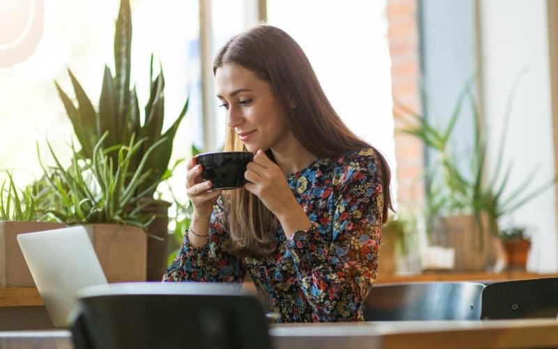 a woman sitting at a table and looking at her computer